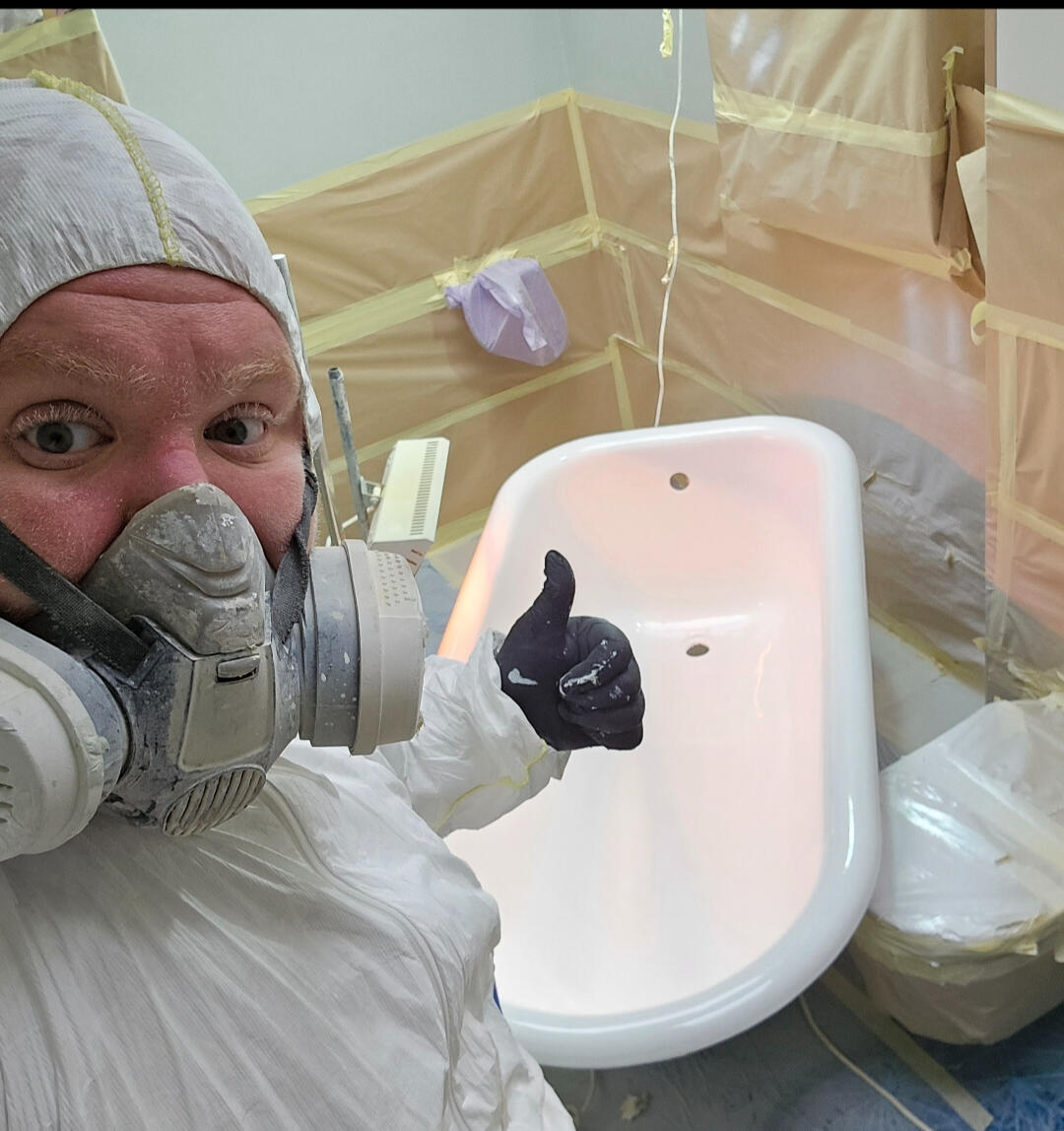 photo of glossy baths owner photo of glossy baths re-enamelling owner Seamus with a thumbs up, in ppe, in a room full of masking up and a completed bath in Swansea